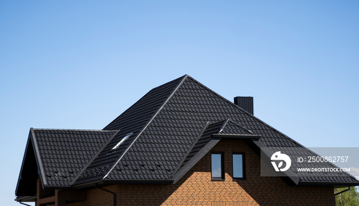 Brown corrugated metal profile roof installed on a modern house with a attic windows. The roof of corrugated sheet. Roofing of metal profile wavy shape. Modern roof made of metal. Metal roofing.