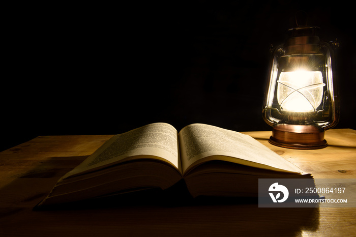 Open book illuminated by a storm lantern