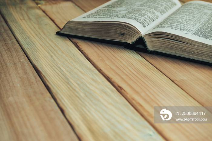 Close up open Bible book on a wooden table background.