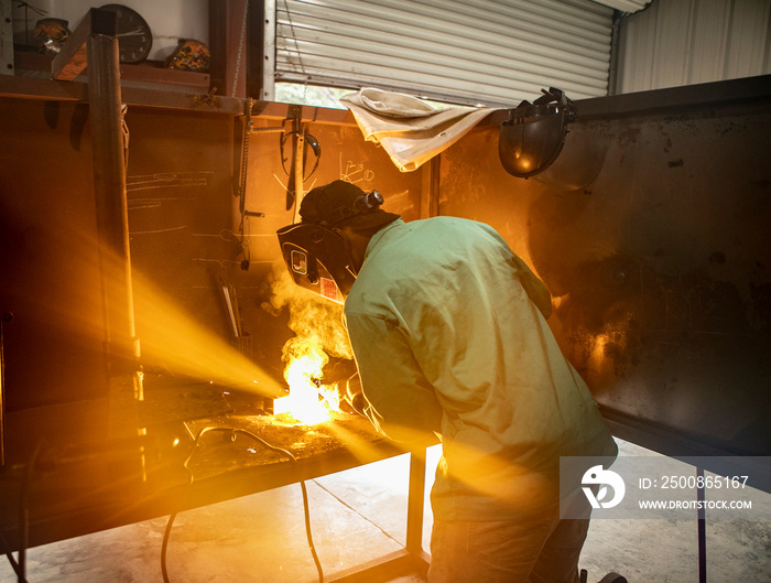 A man welds two pieces of metal together in a shot with an arc welder.