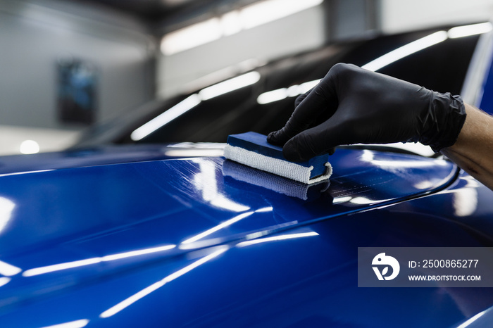 Process of applying ceramic protective coat on body car in detailing auto service. Car service worker apply ceramic coating to protect the car body from scratches.