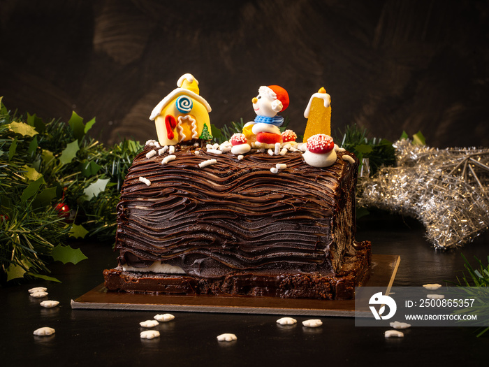 log of chocolate christmas cake with decorations. dark background