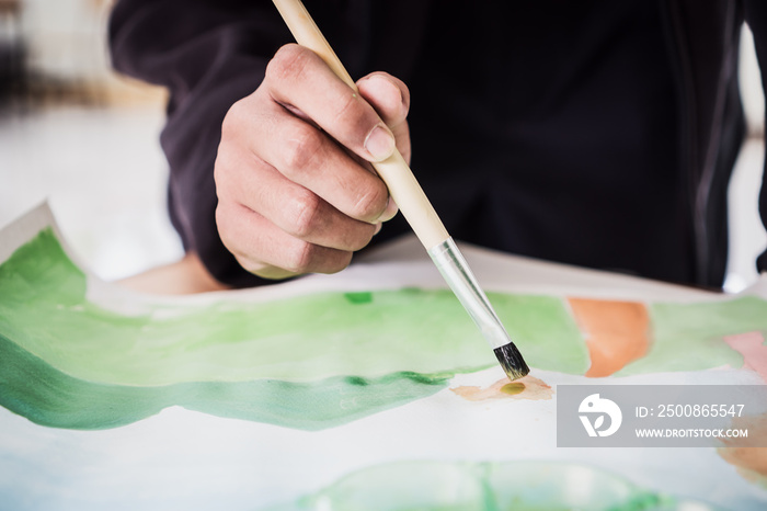 Artist painting watercolor abstract of landscape with brush drawing on paper for creation at studio for relax and hobby. Creative skill Hobbies concept