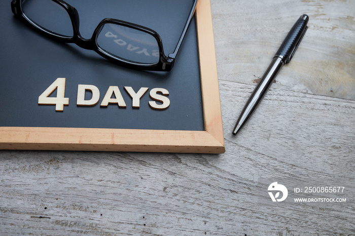 4 DAYS word on the black chalkboard reflected on the eyeglasses. 4 day work week concept