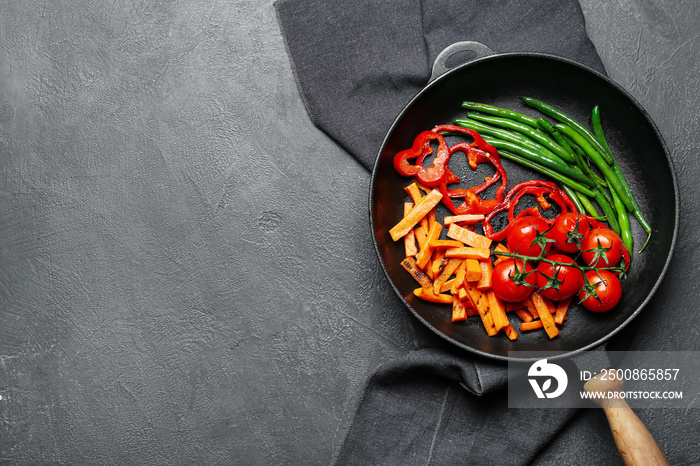 Frying pan with tasty vegetables on dark background