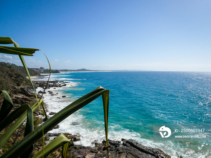 Bright sunny summer beach day with vivid blue ocean in the background and cliffs in the foreground at Point Arkwright, Sunshine Coast, Queensland, Australia