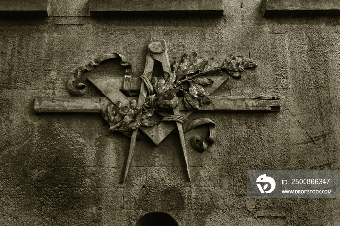 Grunge freemasonry emblem on a dramatic background - masonic triangle and compass, closeup of old architectural building decoration. Masonic sign on the wall of an old house. Odessa, Ukraine