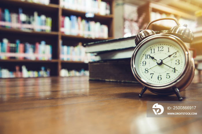 Alarm clock on the table, book, background blur, close-up shot