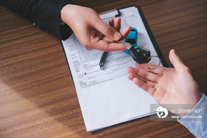 Concept car rental. Close up view Hand of agent giving car key to customer after signed rental contract form.