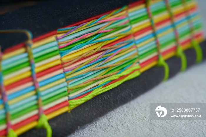 Closeup shot of the braided binding with woven thread and multicolored leaves. recycled book. Handmade agenda