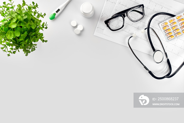 Doctor’s office desk with medical documents, charts, eyeglasses and stethoscope. Top view. Copy space