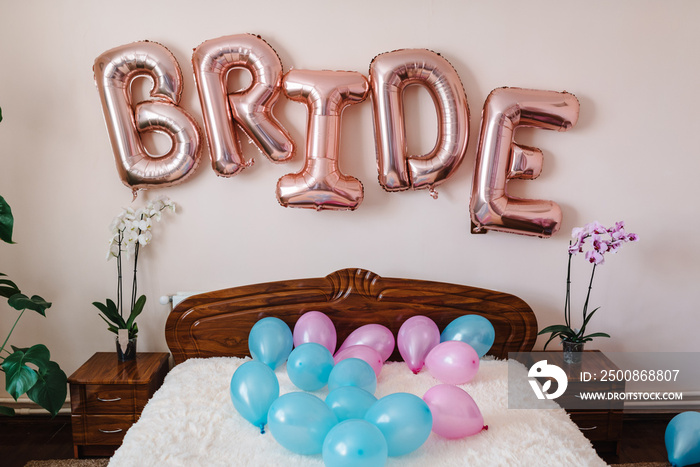 Pink and blue balloons on the bed in the bedroom. Decor for the bride in the room at the wedding.