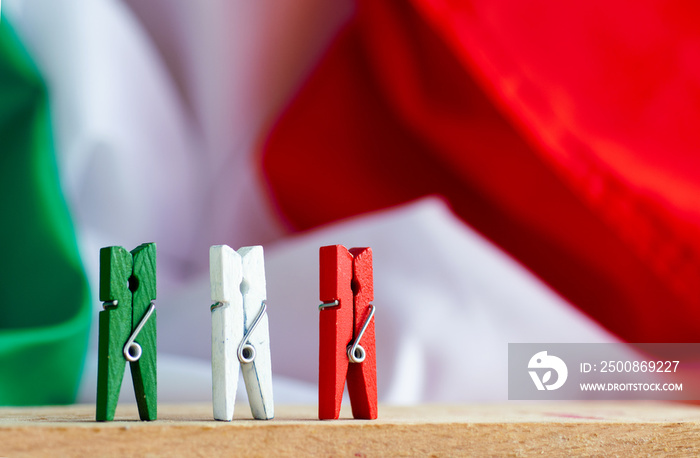 red, white and green clothespin against Italian flag symbolize citizens of Italy - postcard  for national holiday or text information