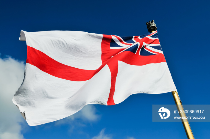 Royal Navy white ensign flying from a warship while docked.