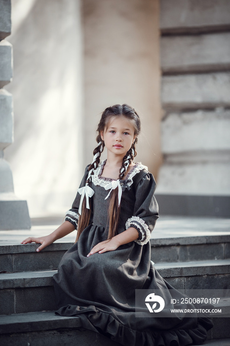 Beautiful little girl in an old dress on the background of the architecture of the historic center