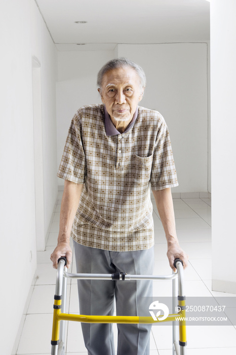 Elderly man walking with a walker at home