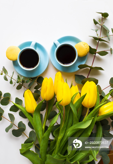 two blue cup of coffee with yellow tulips on an old table, top view