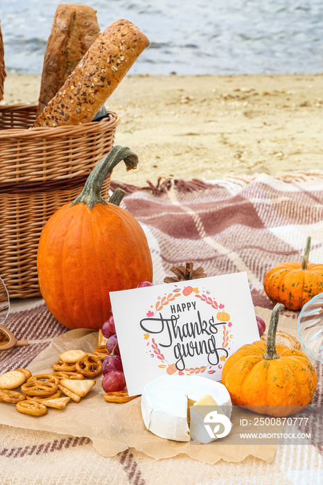 Pumpkins, delicious food and card with text HAPPY THANKSGIVING on beach