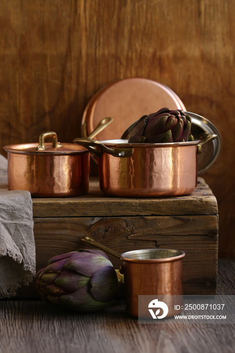 copper utensils, pots, ladle and pan on wooden background