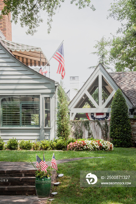 USA Patriotic banners and flags on pretty vintage upscale house with nice landscaping - back yard