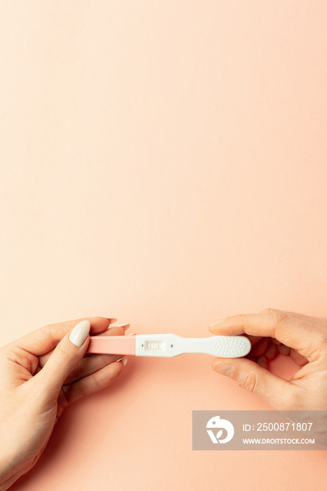 Pregnancy test kit. Female hand hold positive pregnant test with silk ribbon on pink background. Medical healthcare gynecological, pregnancy fertility maternity people concept.