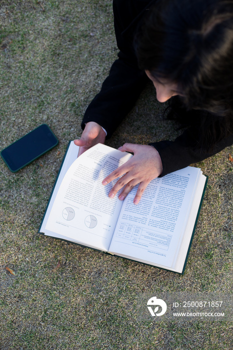 close-up of young woman lying on the lawn reading a book. Concept of hobbies, lifestyle and learning.