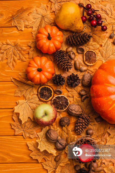 Top view of burning candle with autumnal decoration on wooden background