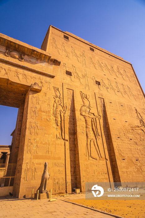 Facade with drawing of pharaohs of the Temple of Edfu in the city of Edfu, Egypt. On the bank of the Nile river, geco-Roman construction, temple dedicated to Huros