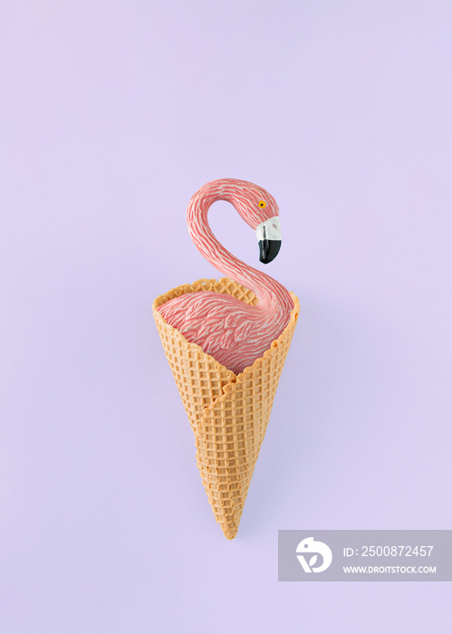 Minimal summer composition with flamingo standing in in ice cream cone on isolated pastel purple background. Summer vacation concept. Top view.