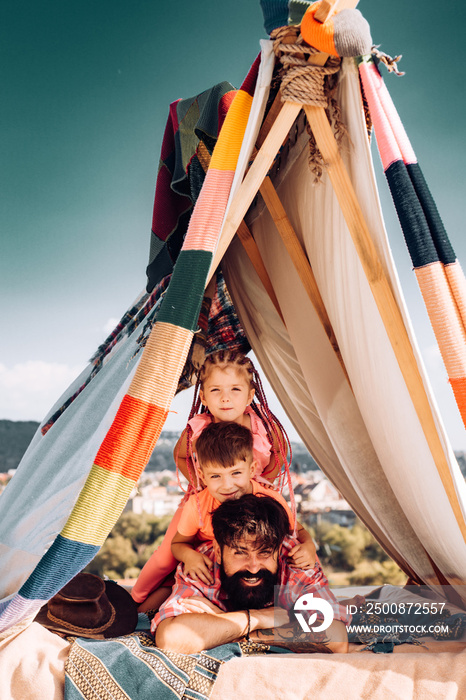 Dad with kids playing in tent. Summer family weekend. Happy father with childrens. Summertime camping. Fathers day. Outdoor family vacation.