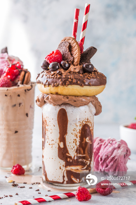 Chocolate indulgent frosting exreme milkshake with donut  and sweets. Crazy freakshake food trend. Copy space