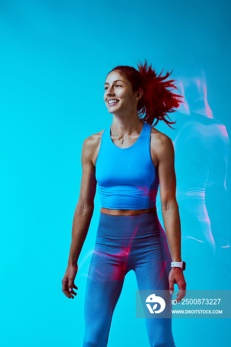 A happy sportswoman exercising in studio isolated on blue background. Long exposure capture motion.