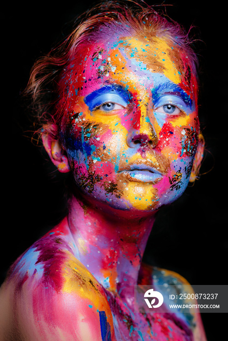 Portrait of a woman with colorful paint brushstroken on face. Bright blue eyes. Advertising Space