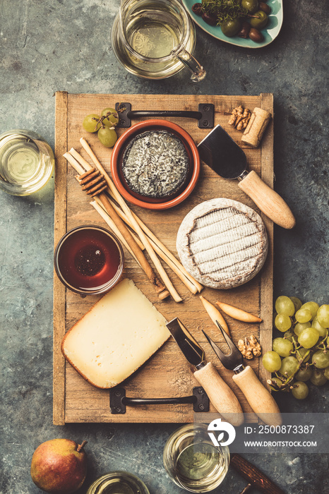 Glasses of white sparkling wine with cheese, grapes, nuts , olives and honey