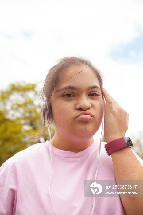 Young mid-sized woman with Down syndrome wearing headphones and fitness watch