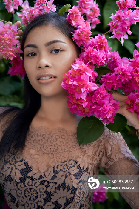 Asian girl portrait face in pink flowers. Beautiful Balinese women. Beauty salon and massage spa concept