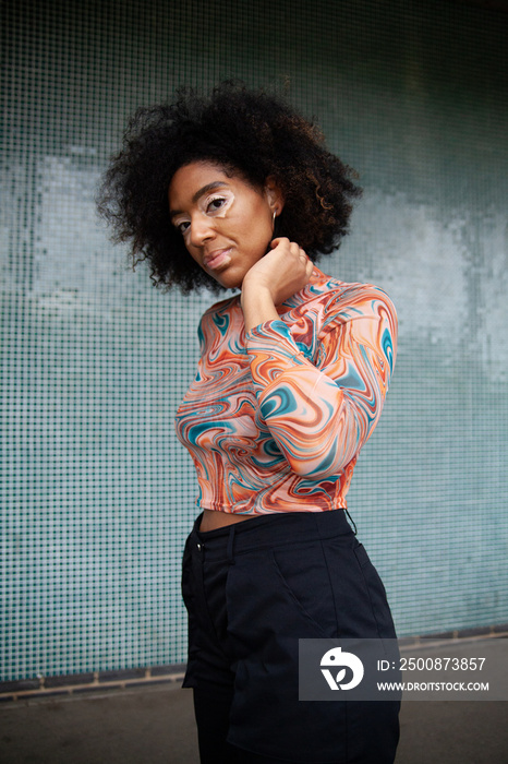 Young curvy woman with vitiligo posing in front of fun tiled wall