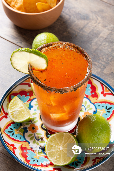 Homemade michelada cocktail with beer, lime juice,hot sauce,salted rim and tomato juice on wooden table