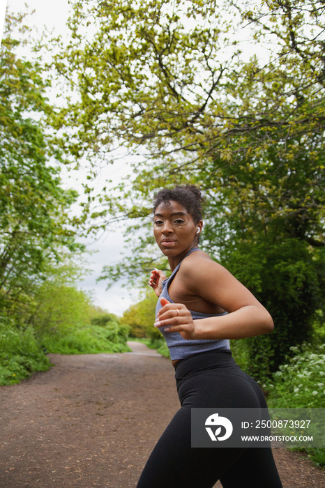 Young curvy woman with vitiligo working out in the park wearing earbuds