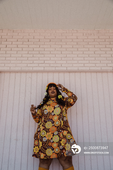 plus size Black woman wearing retro dress standing against pink wall