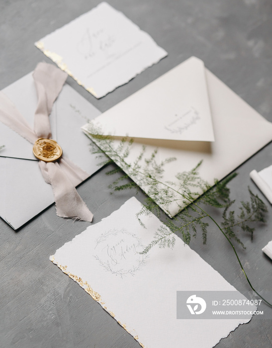 Wedding details flat lay. Wedding invitation and scroll paper. Bottle with fragrance. Ring box. Simple bouquet.