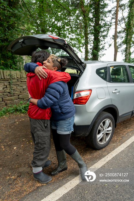 Mother and son hugging by car after hike