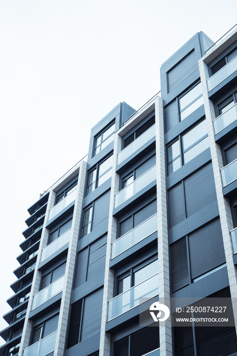 A grey blue facade of a modern multistory residential building, house view from a bottom up. Home details of the exterior, architecture of a metropolis. Construction, real estate investment concept.