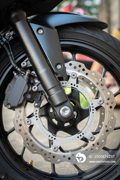 Closeup detail of sport racing motorcycle wheel and ABS brakes system with front suspension shock absorber conventional telescopic fork 320 mm disc 2 piston caliper stopping power ABS.