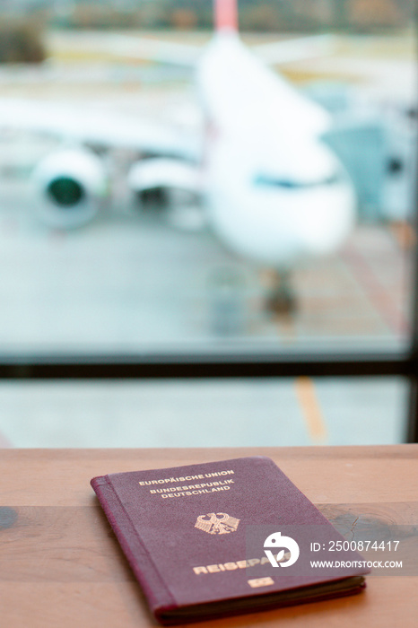 German Passport on table at airport, blur airplane in the background