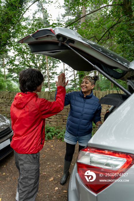Mother and son high fiving by car after hike
