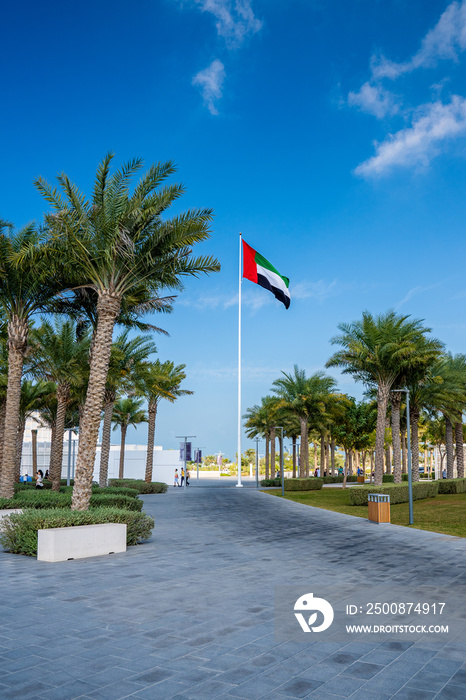 A United Arab Emirates flag flying against clean and tranquil sky.