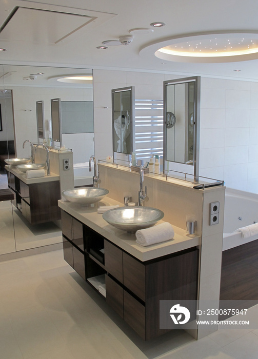 Modern design interiors inside bathroom with bathtub double vanity sink, glas shower, mirror, towels and window to suite cabin stateroom on yacht cruiseship or cruise ship liner