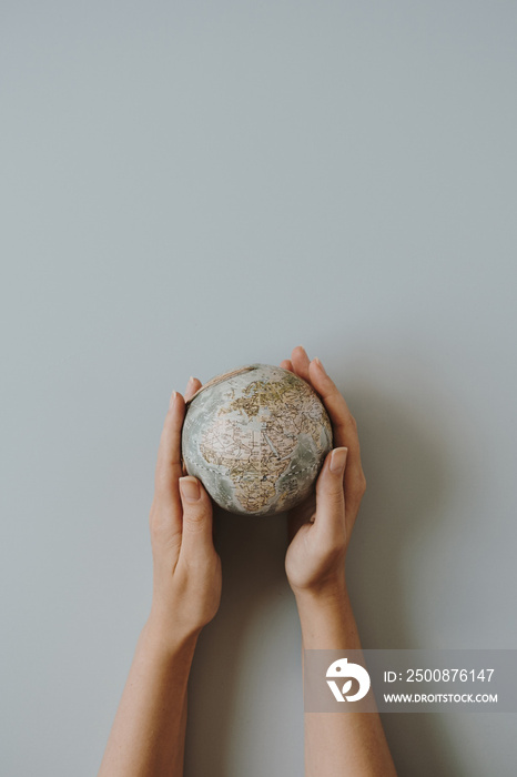 Globe model in female hands on blue background. Save the world, planet Earth concept. Women’s rights and power concept