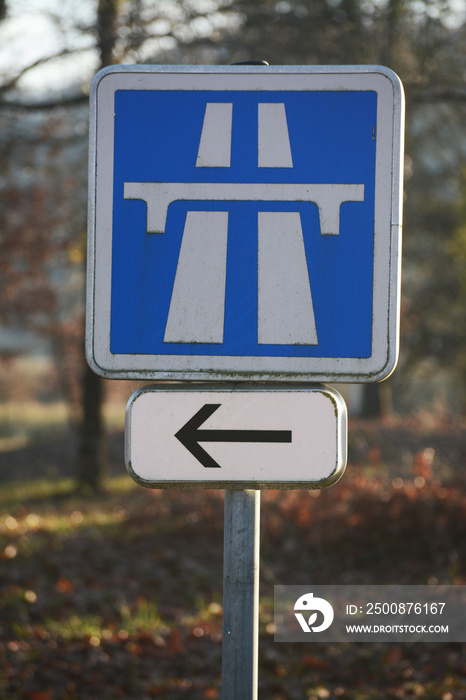 Panneau bleu avec flèche indiquant la direction d’une autoroute.